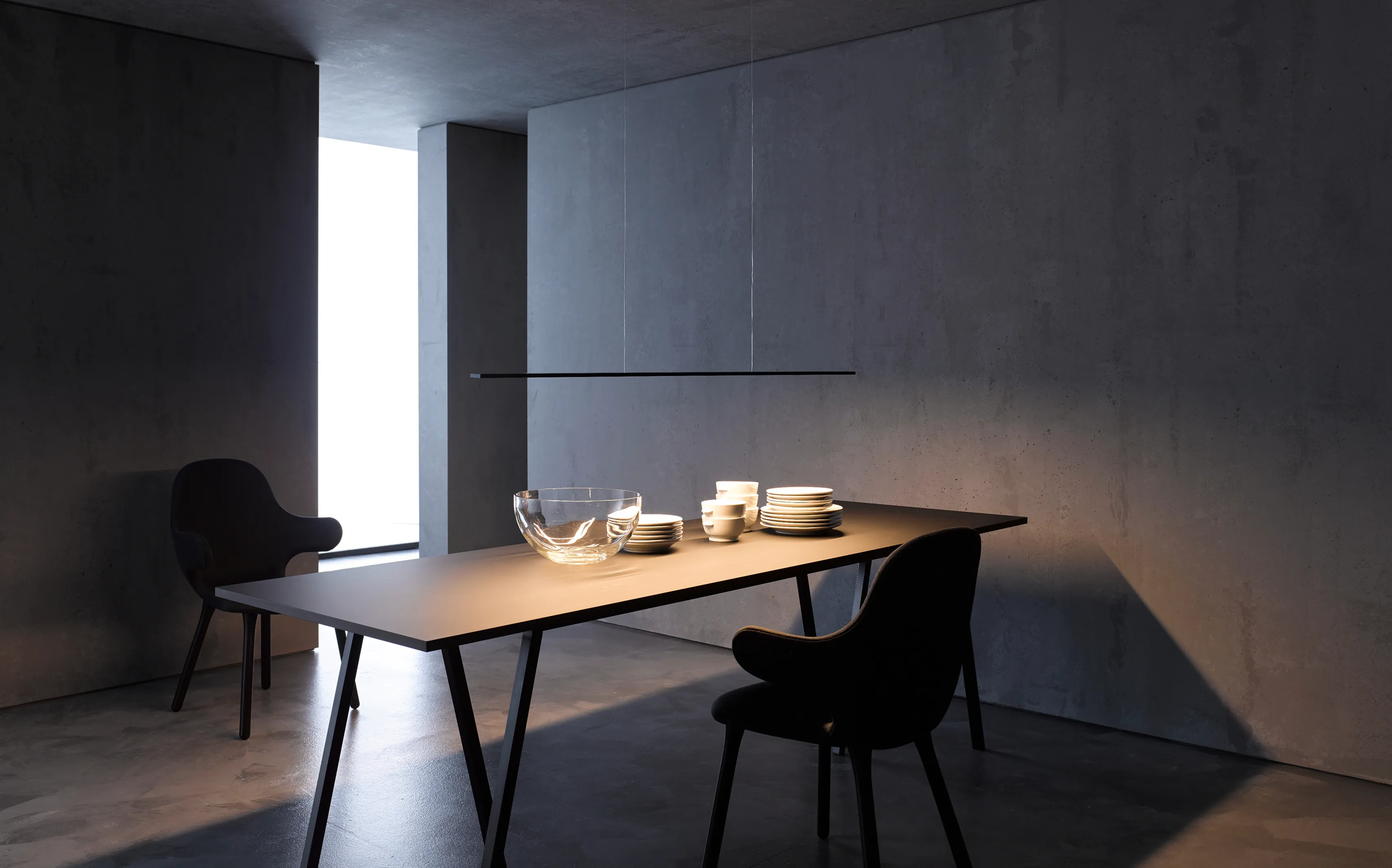 Minimalistischer Esstisch beleuchtet mit Pendelleuchte GERA Horizon in dunklem, betonfarbenem Raum.