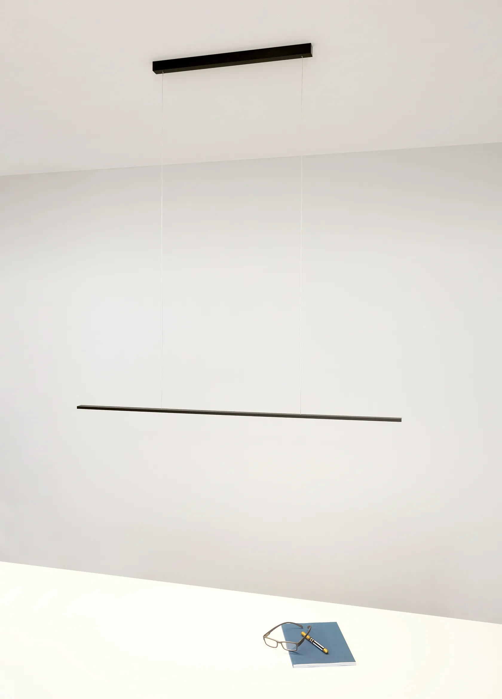 Minimalistische schwarze Pendelleuchte GERA Horizon über einem Schreibtisch