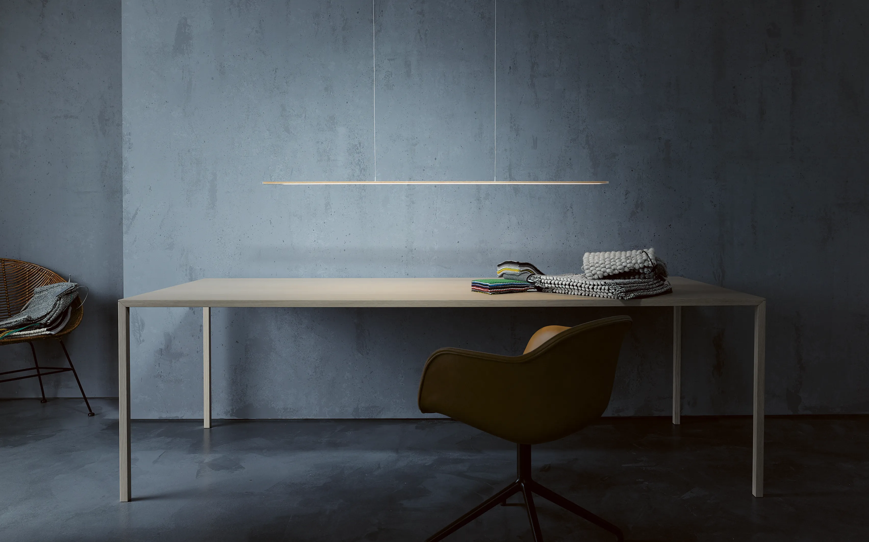 Pendelleuchte GERA Twig über einem hellen Holztisch vor einer grauen Betonwand.