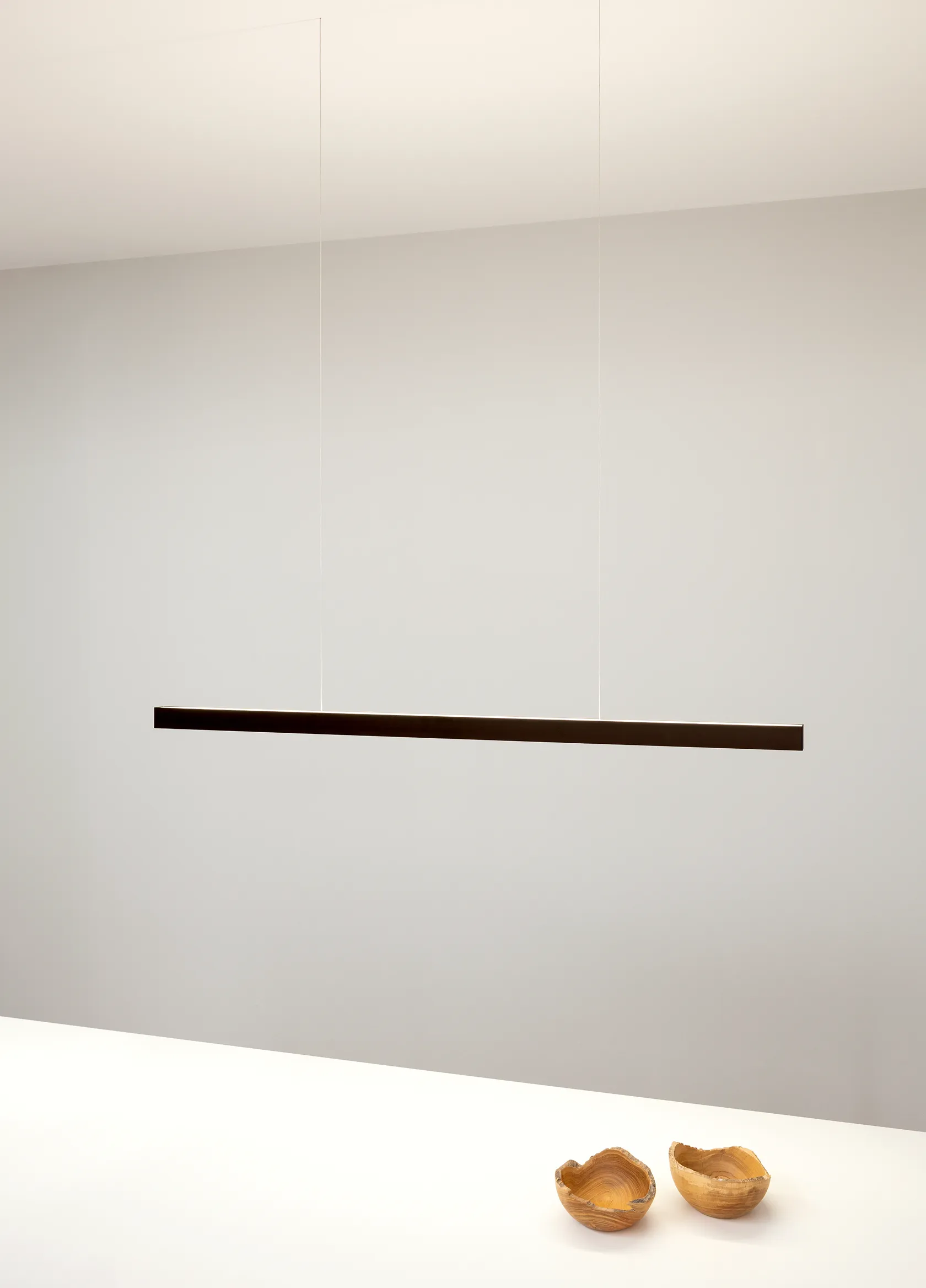 Pendelleuchte GERA Quadra Swing über einem Tisch mit zwei kleinen Holzschalen.