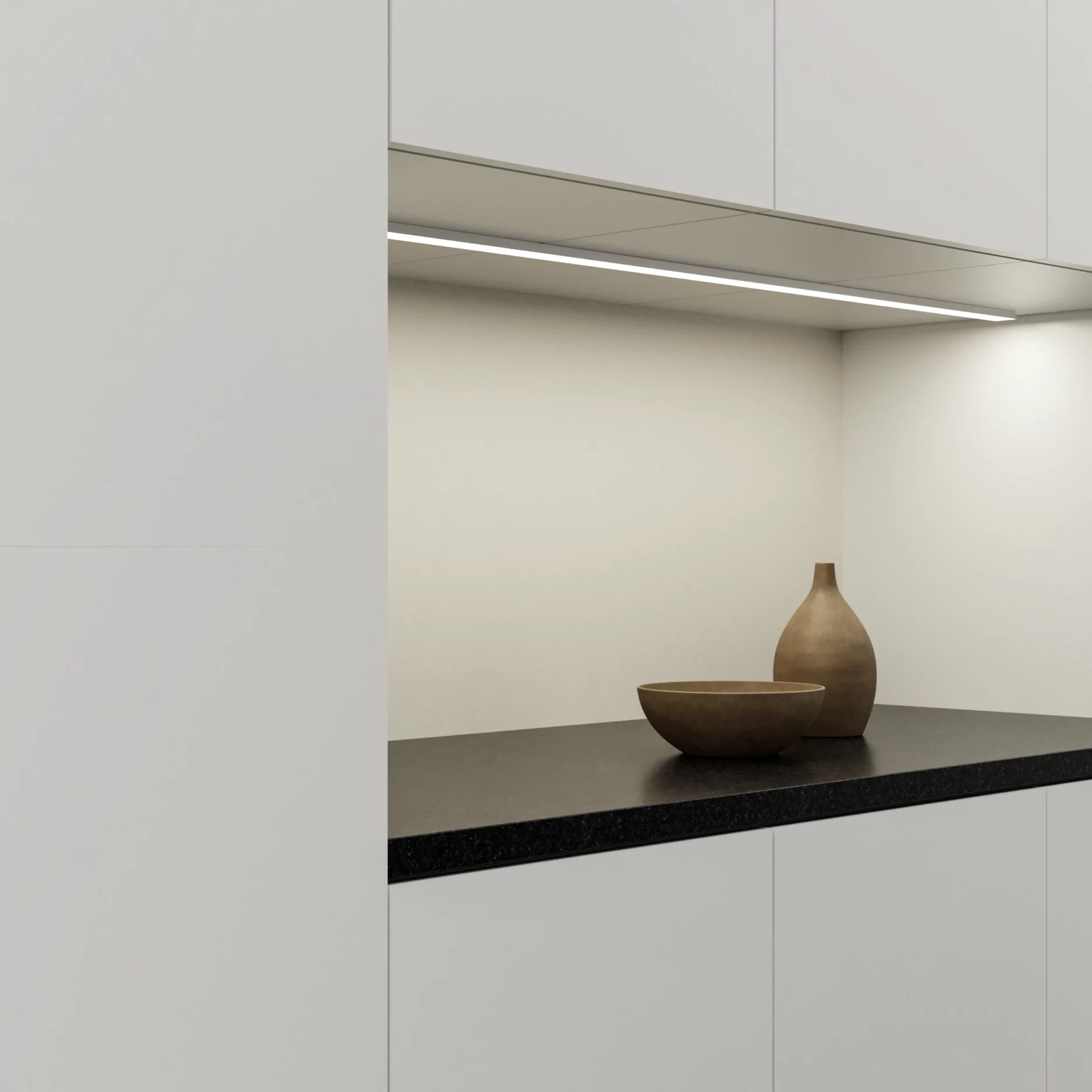 GERA Unterbauleuchte 32×10 montiert unter einem Küchenschrank, eine dunkle Granitarbeitsfläche mit Schale und Vase beleuchtend.