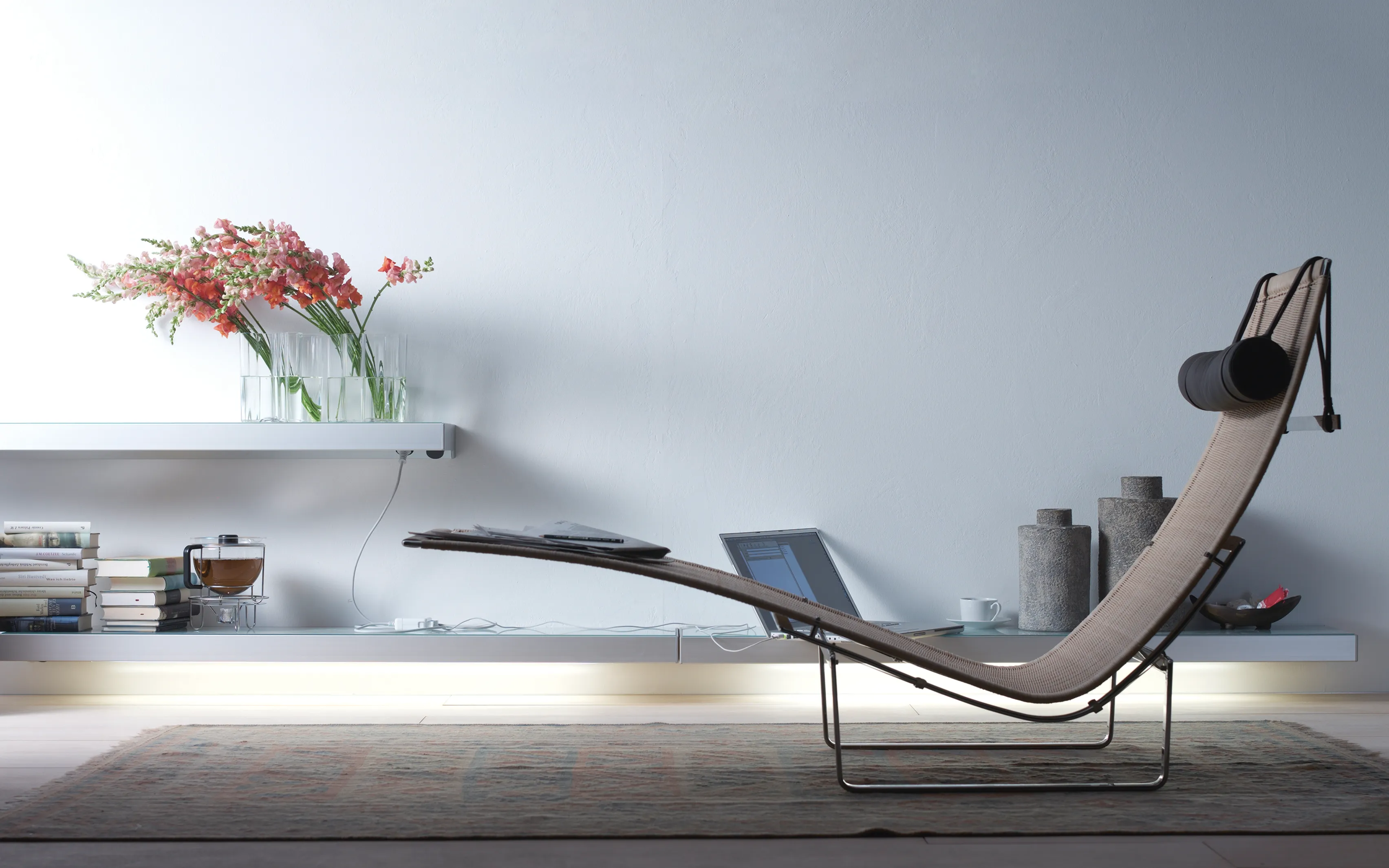 Moderne Chaiselongue vor einem Lichtbord GERA One mit Laptop und Blumenstrauß.