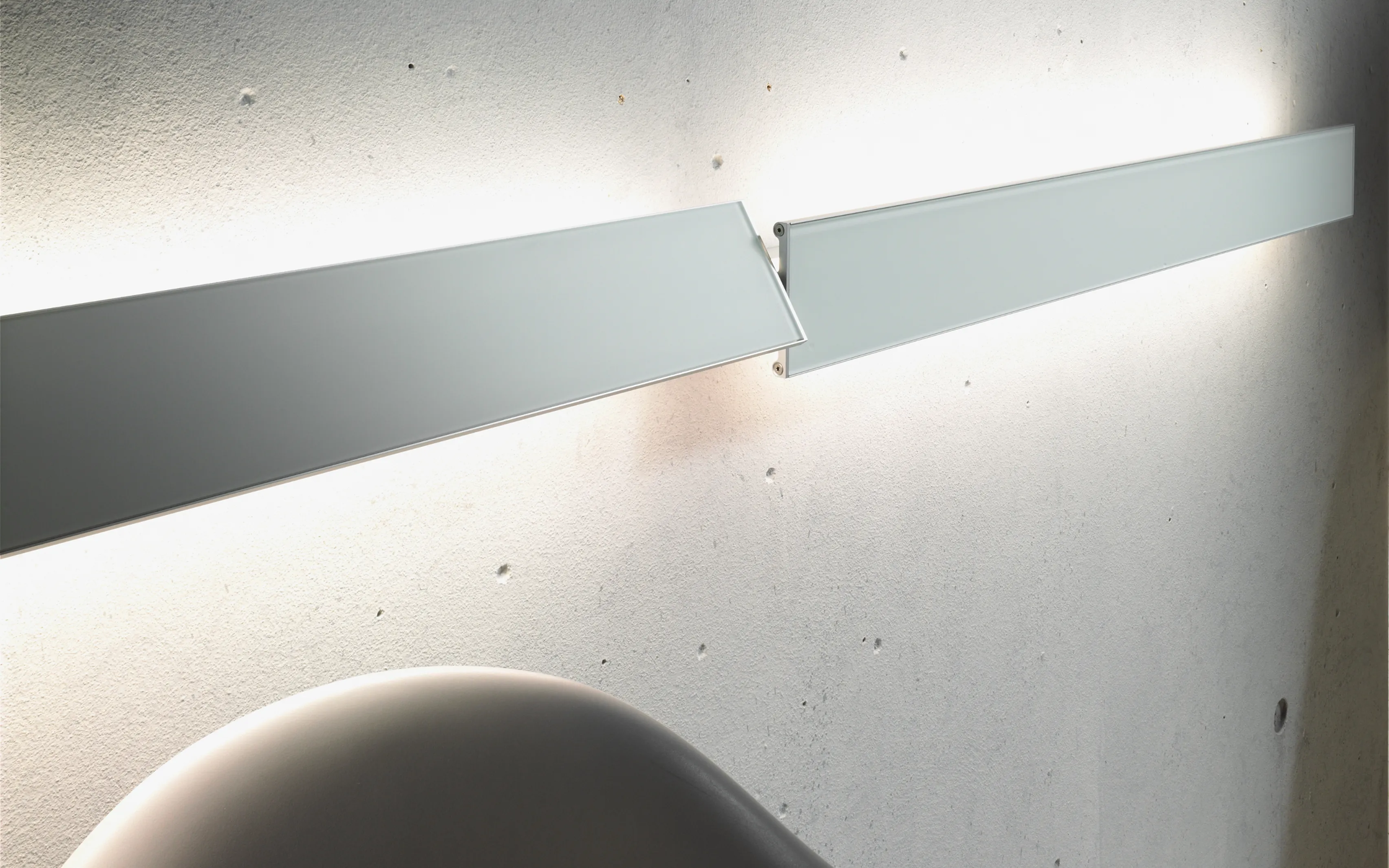 Zwei GERA Slant Leuchten mit unterschiedlicher Winkelung vor Sichtbetonwand.