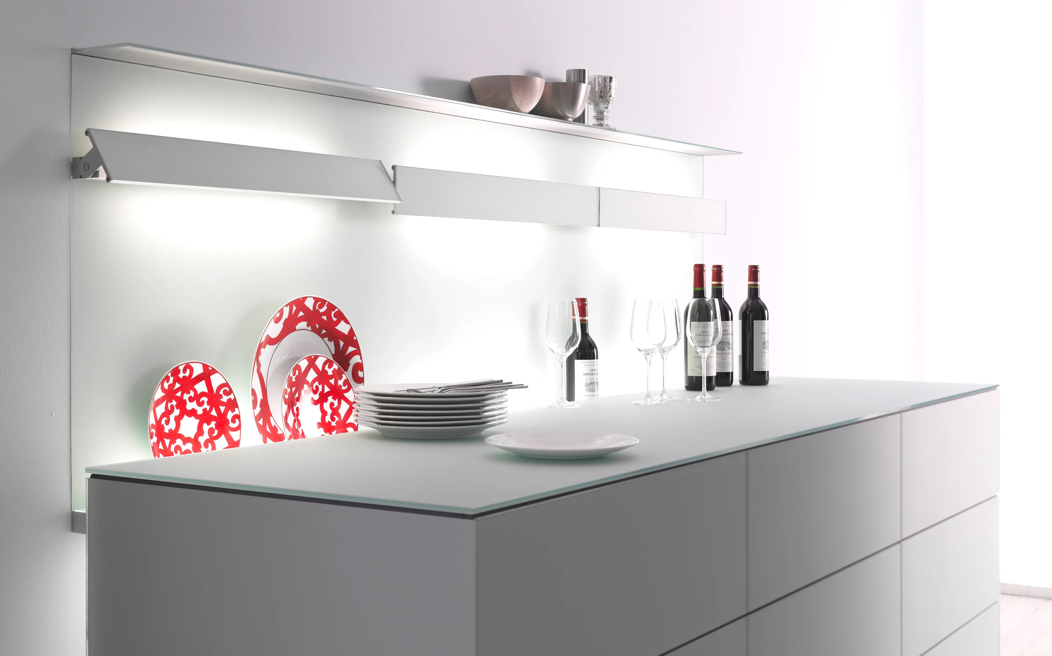 Moderne helle Küche mit Kücheninsel, hinterleuchteter Nischenrückwand mit drei GERA Slant Wandleuchten und dekorativen Tellern.