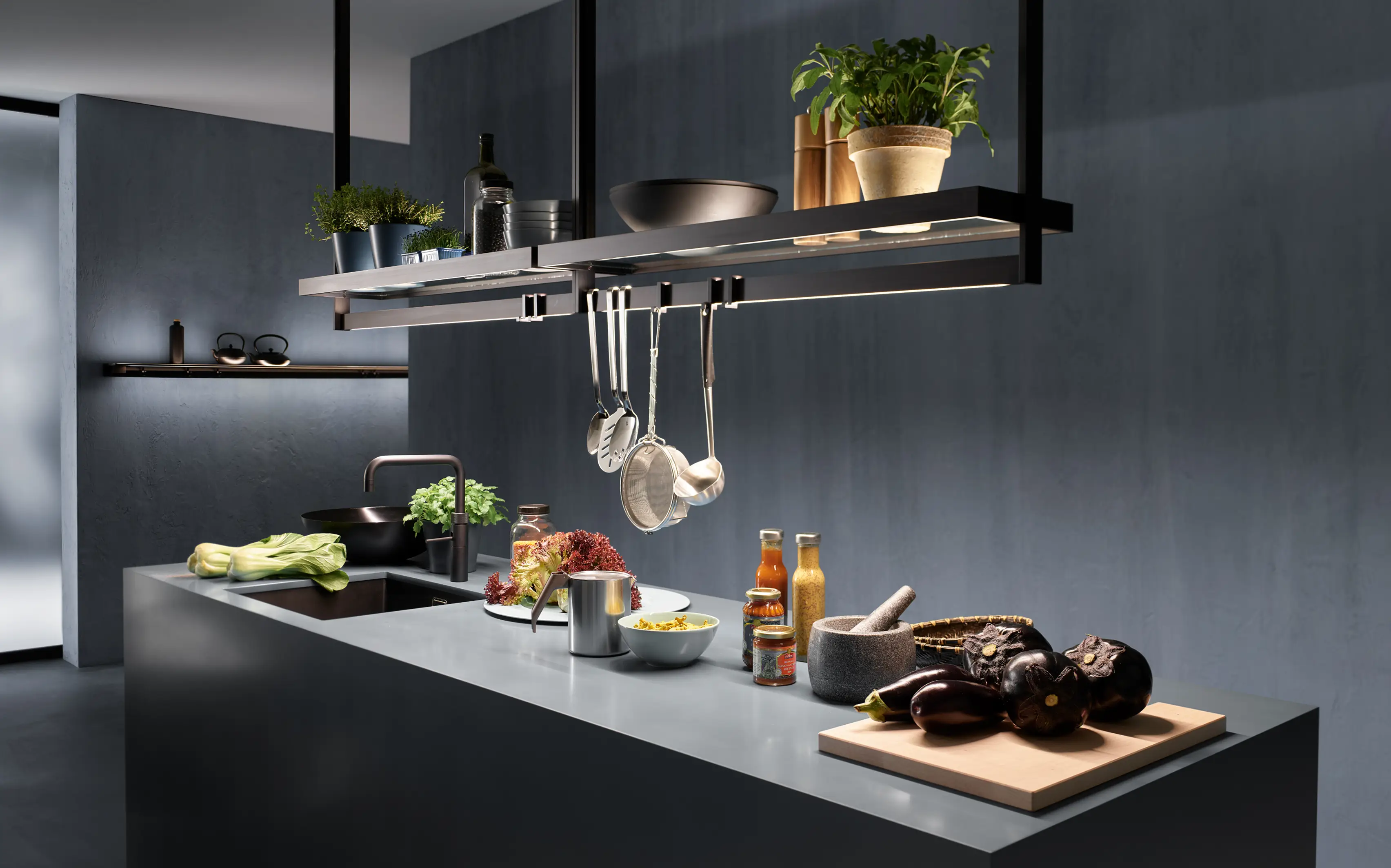 Moderne Kücheninsel mit Lichtbrücke GERA Lucina, Kochutensilien und frischem Gemüse.