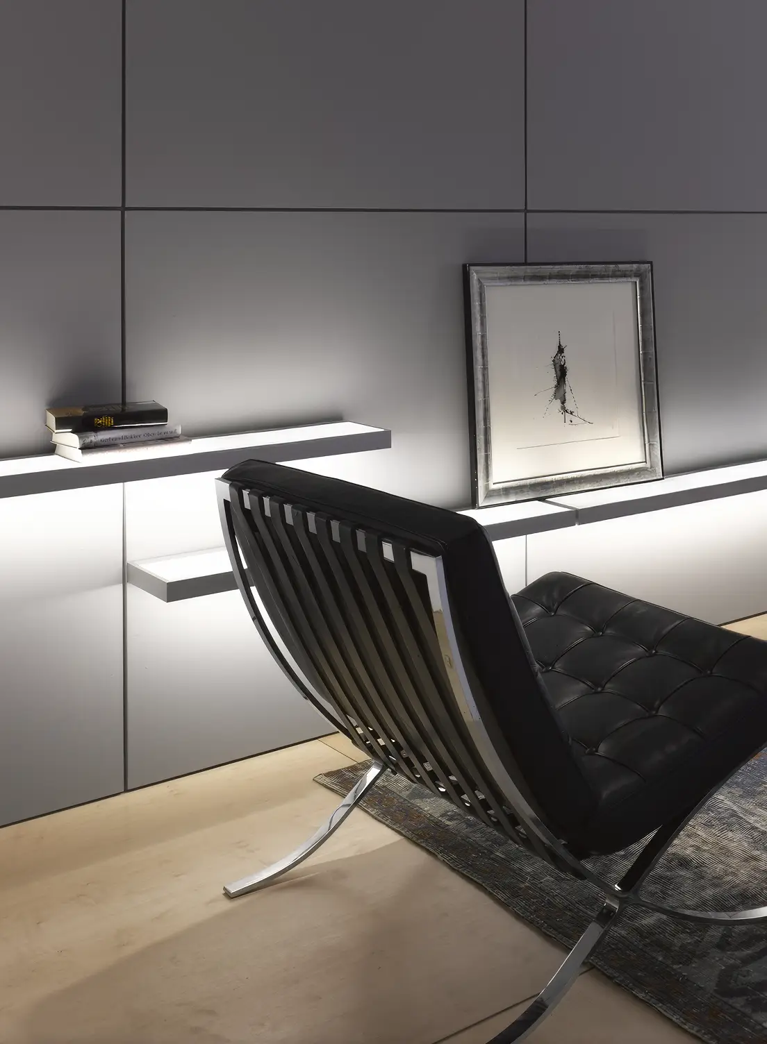 Modernes minimalistisches Wohnzimmer mit zwei schwarzen Barcelona-Sesseln auf einem orientalischen Teppich vor beleuchteten GERA Add Lichtbords.