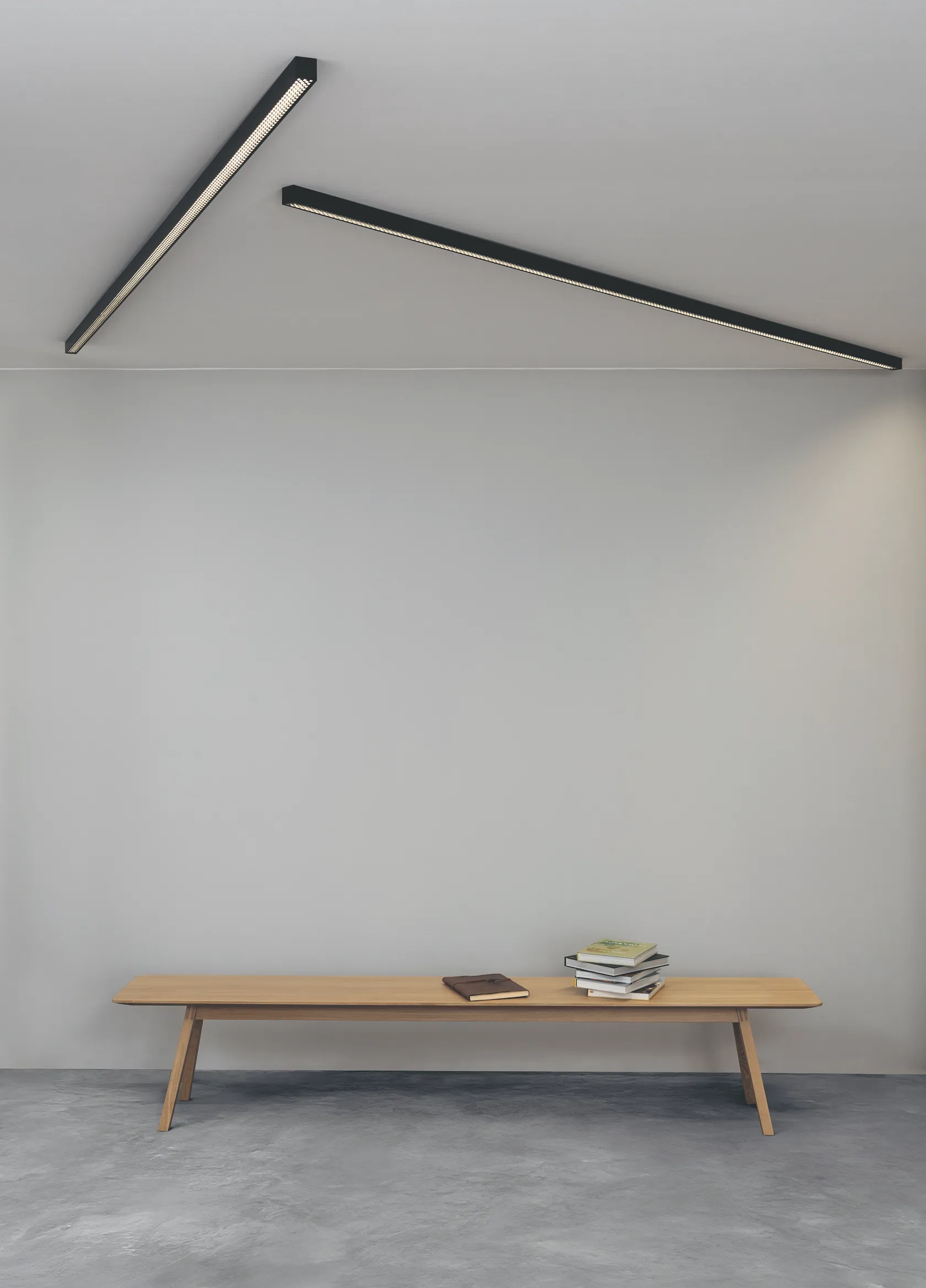 Minimalistische Holzbank vor weißer Wand mit schwarzen GERA Quadra Deckenleuchten.