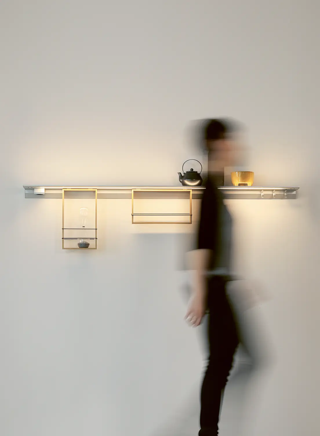 Wandleuchte GERA Feature mit Ablagefächern und vorbeilaufender, unscharfer Person.