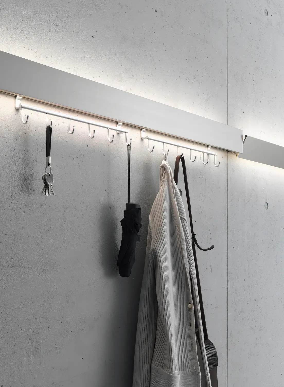 Garderobenleuchte GERA Hook mit integrierter Beleuchtung an einer Sichtbetonwand.