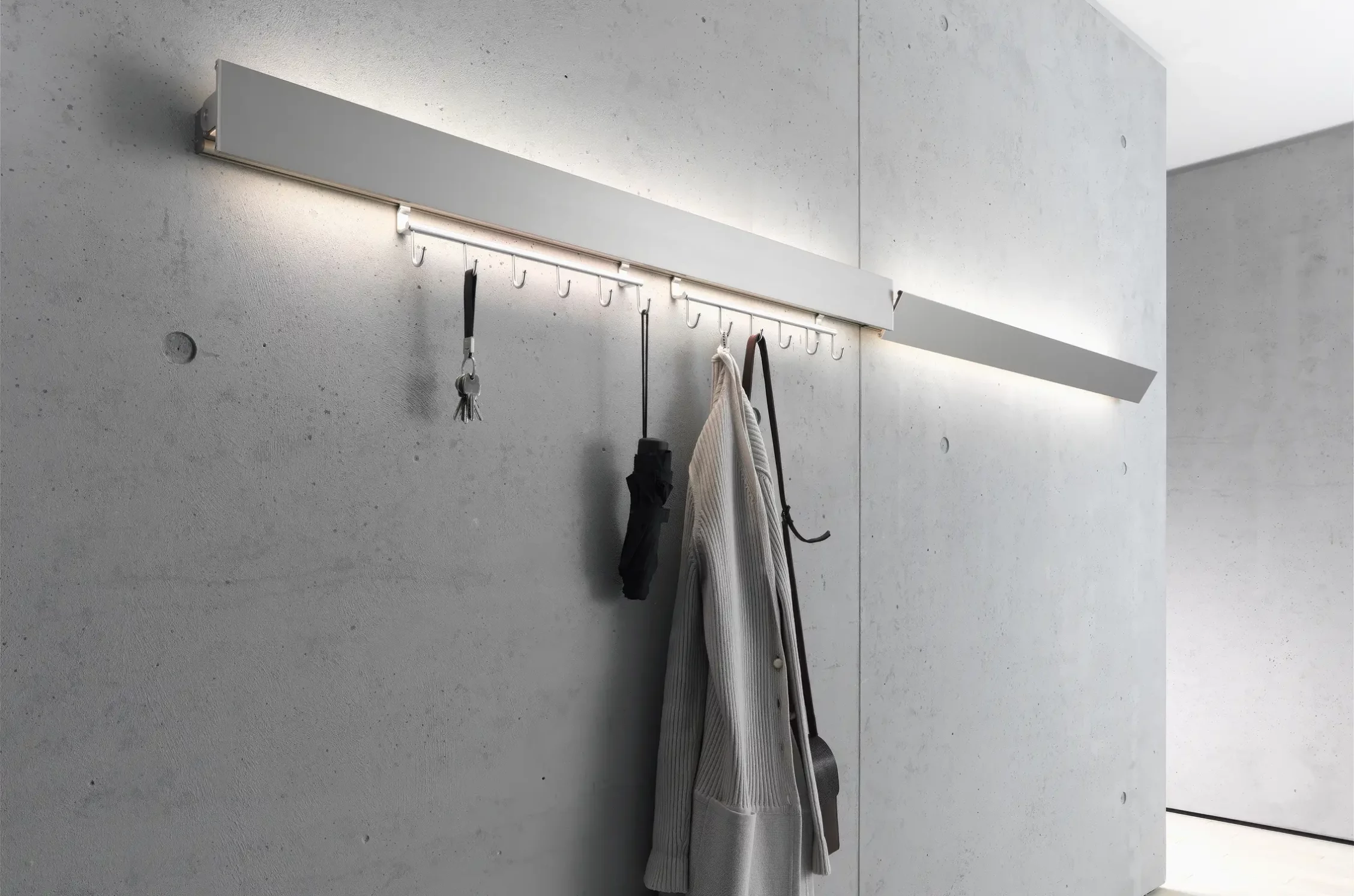 Garderobenleuchte GERA Hook mit integrierter Beleuchtung an einer Sichtbetonwand.