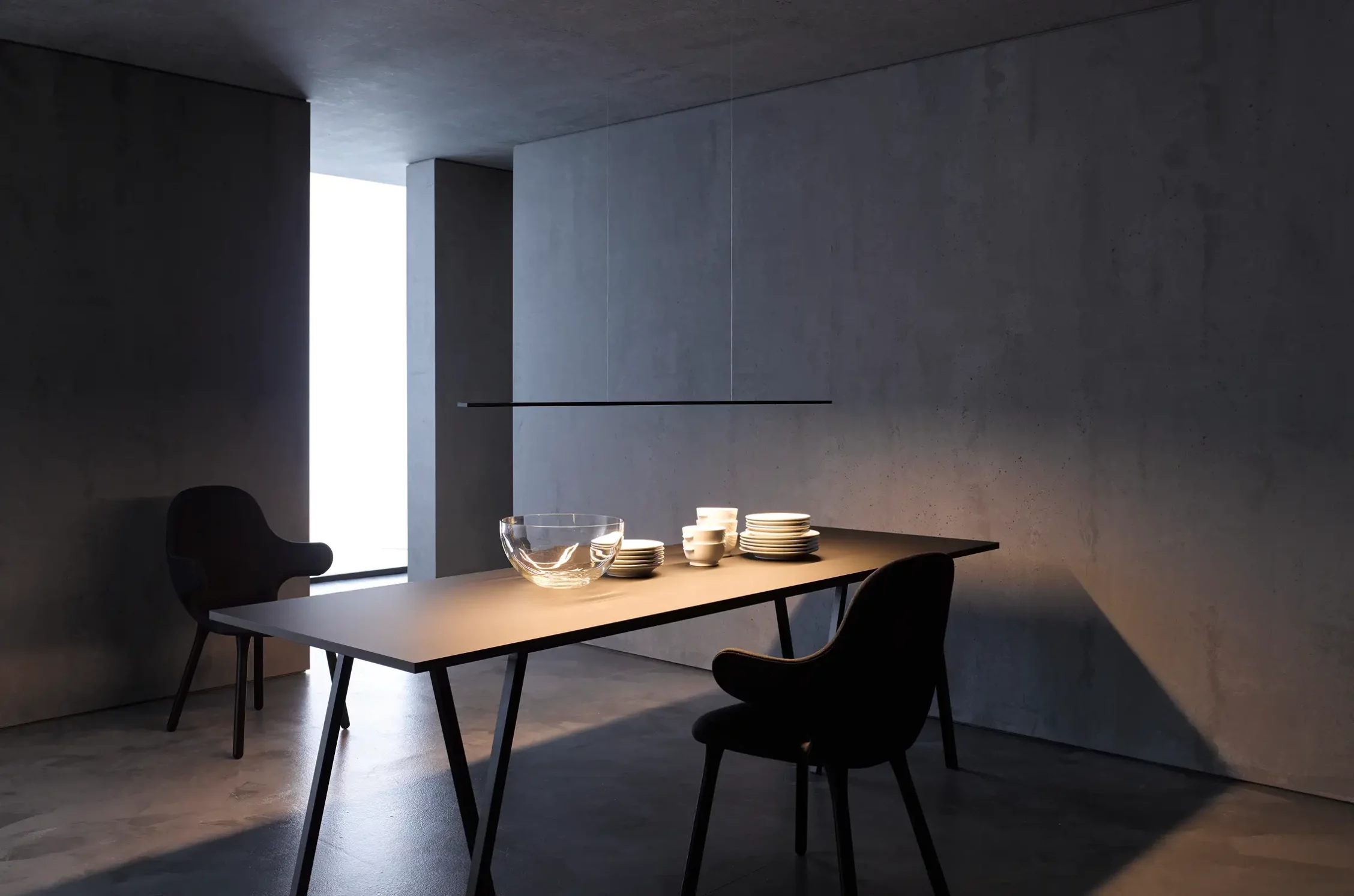 Minimalistischer Esstisch beleuchtet mit Pendelleuchte GERA Horizon in dunklem, betonfarbenem Raum.