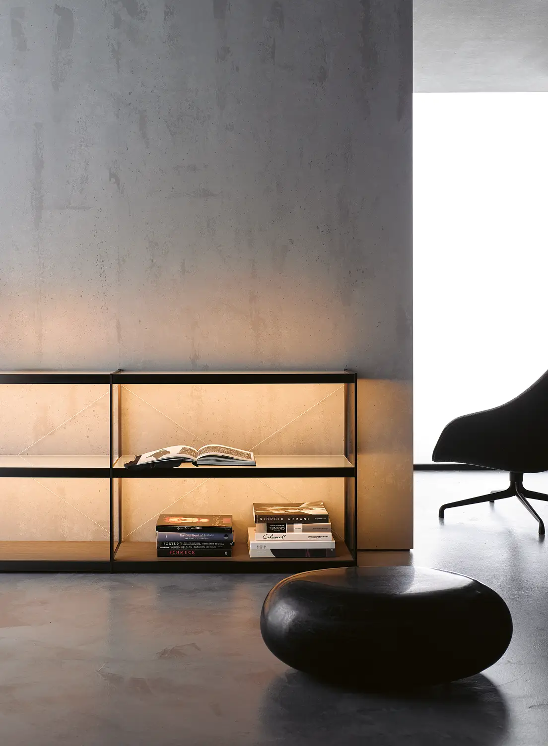 Beleuchtetes Sideboard GERA Item Twin vor einer grauen Betonwand mit einem schwarzen Hocker und einem Sessel.