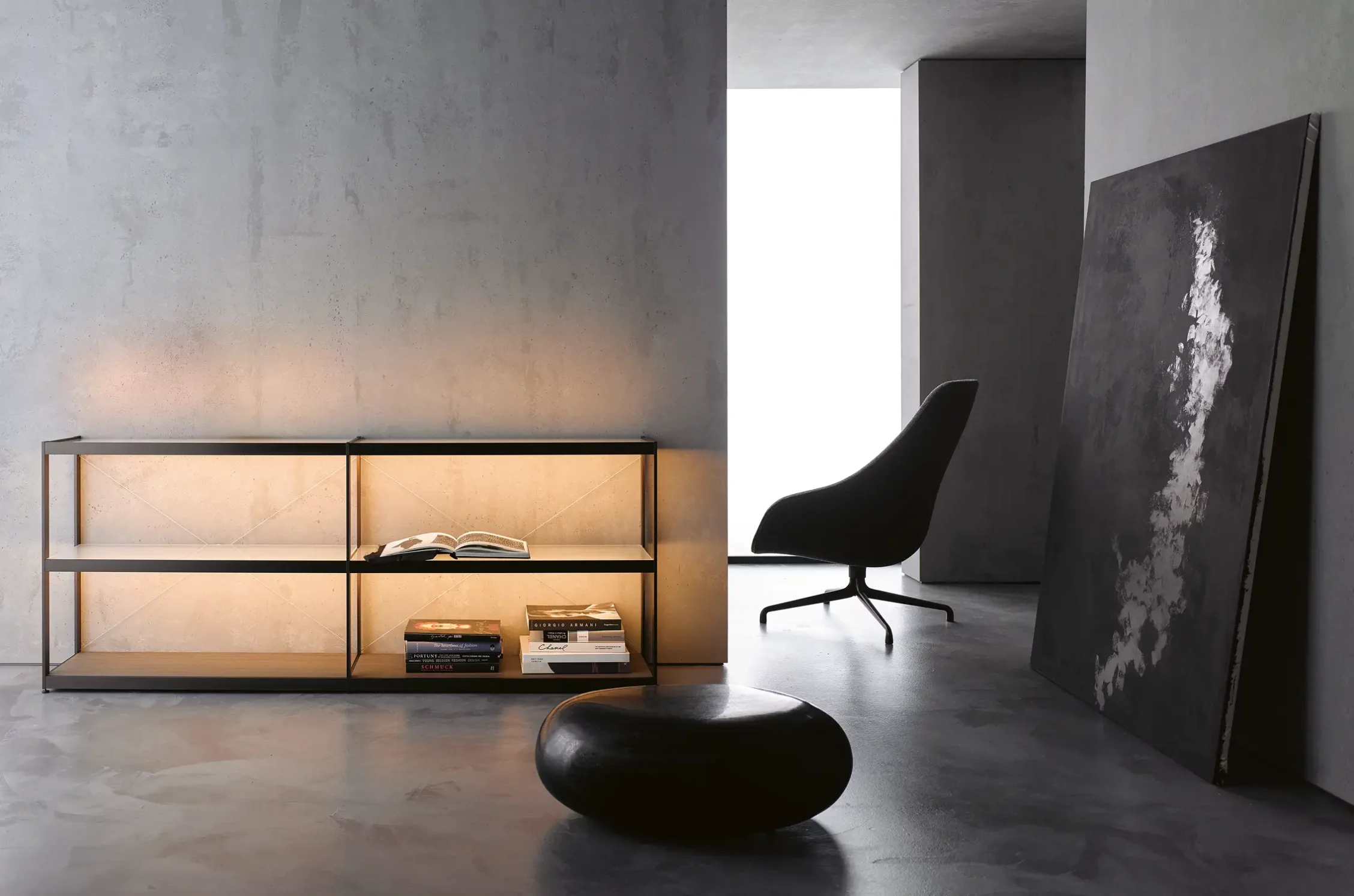 Beleuchtetes Sideboard GERA Item Twin vor einer grauen Betonwand mit einem schwarzen Hocker und einem Sessel.