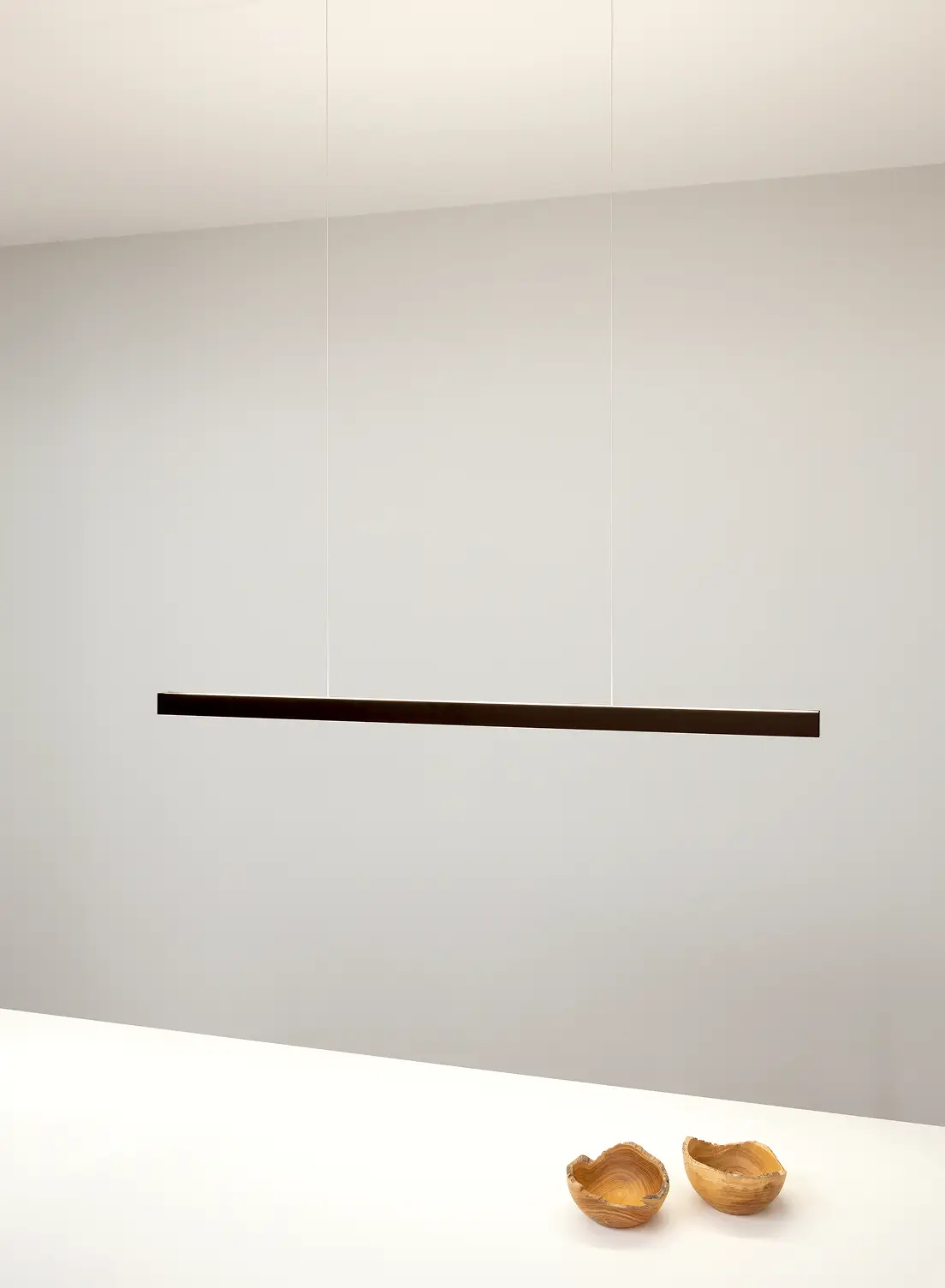 Pendelleuchte GERA Quadra Swing über einem Tisch mit zwei kleinen Holzschalen.