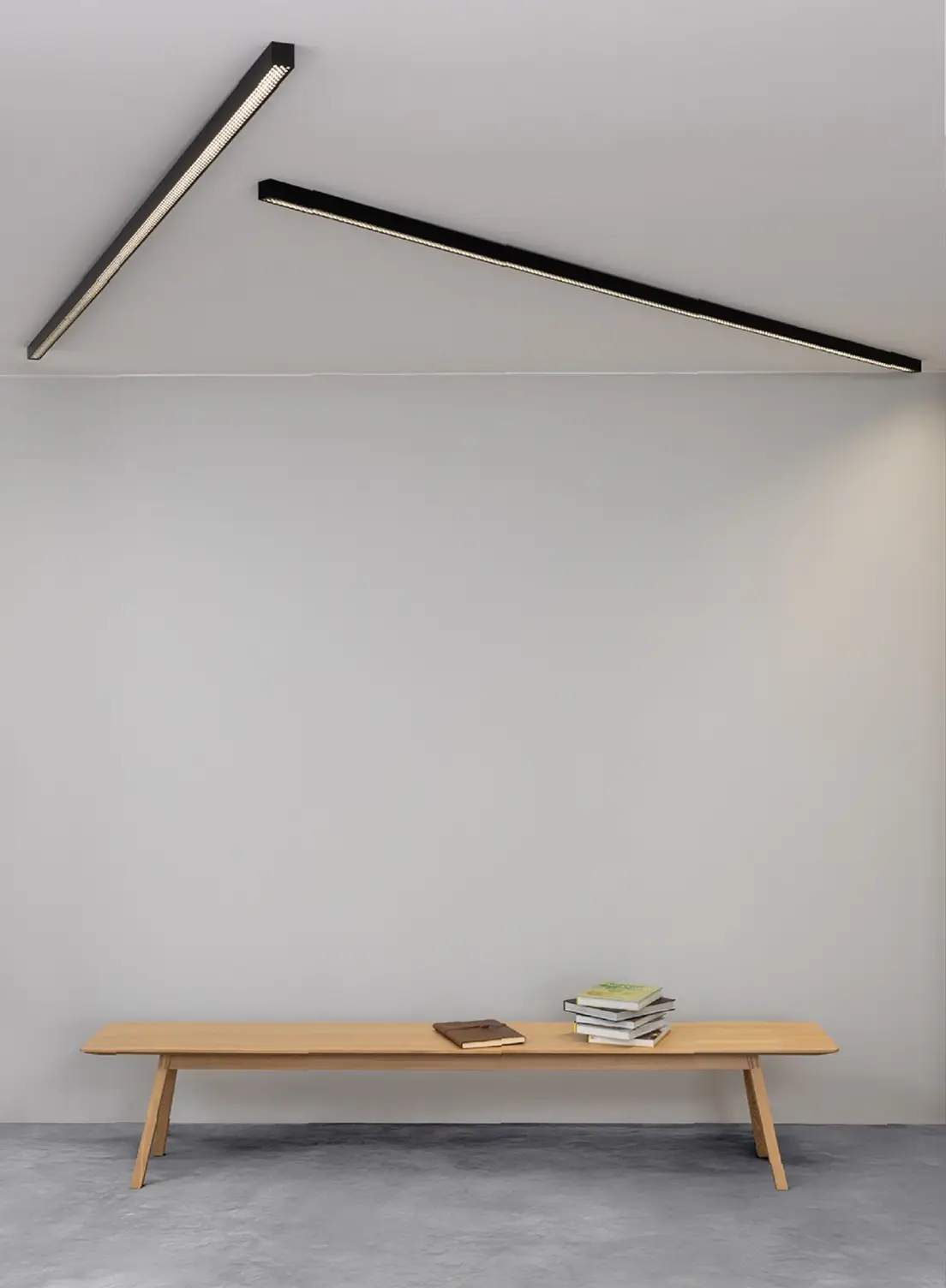 Minimalistische Holzbank vor weißer Wand mit schwarzen GERA Quadra Deckenleuchten.