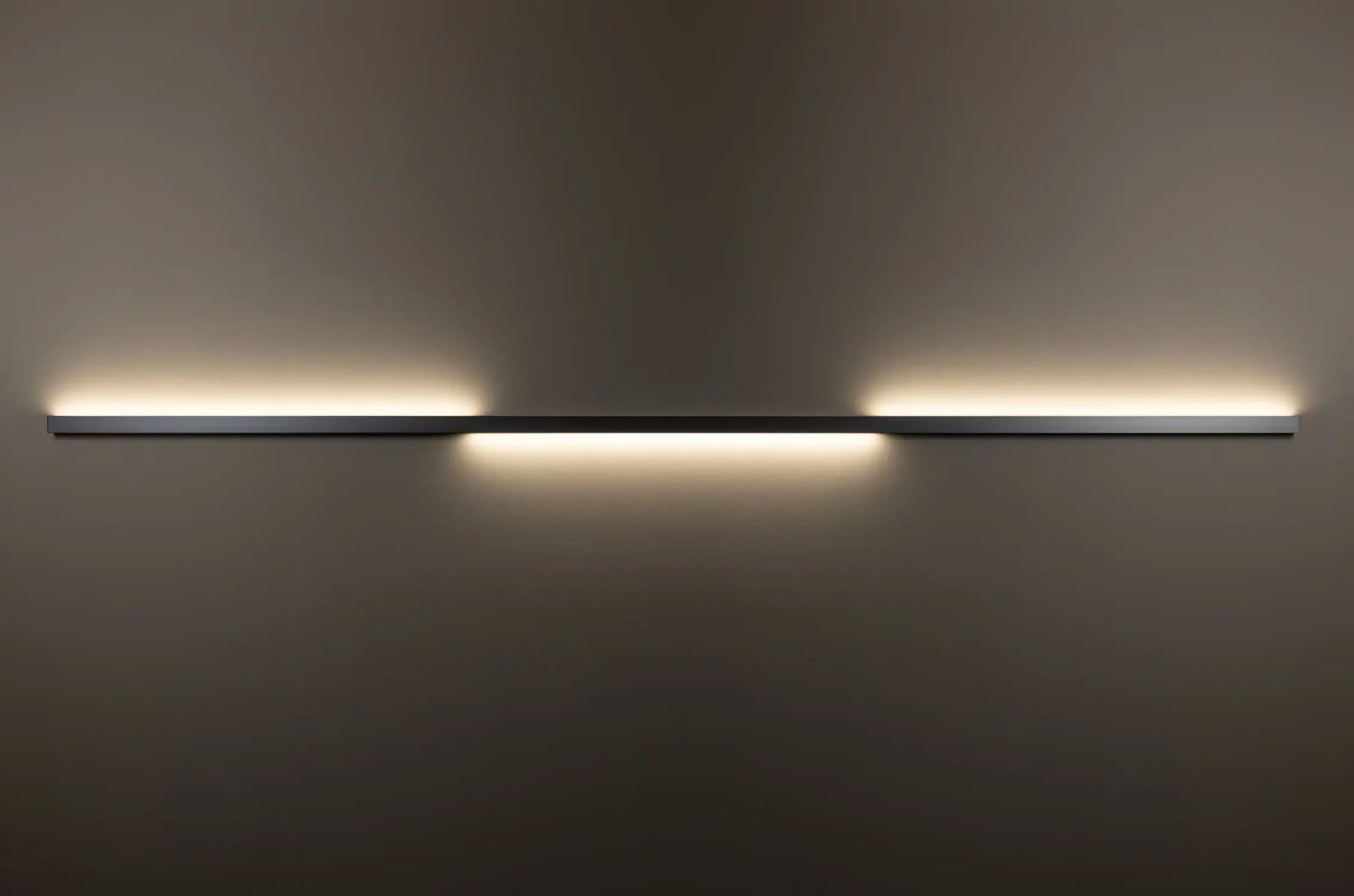 Horizontal installierte Wandleuchte GERA Quadra Wall wirft Licht nach oben und unten auf dunkle Wand.