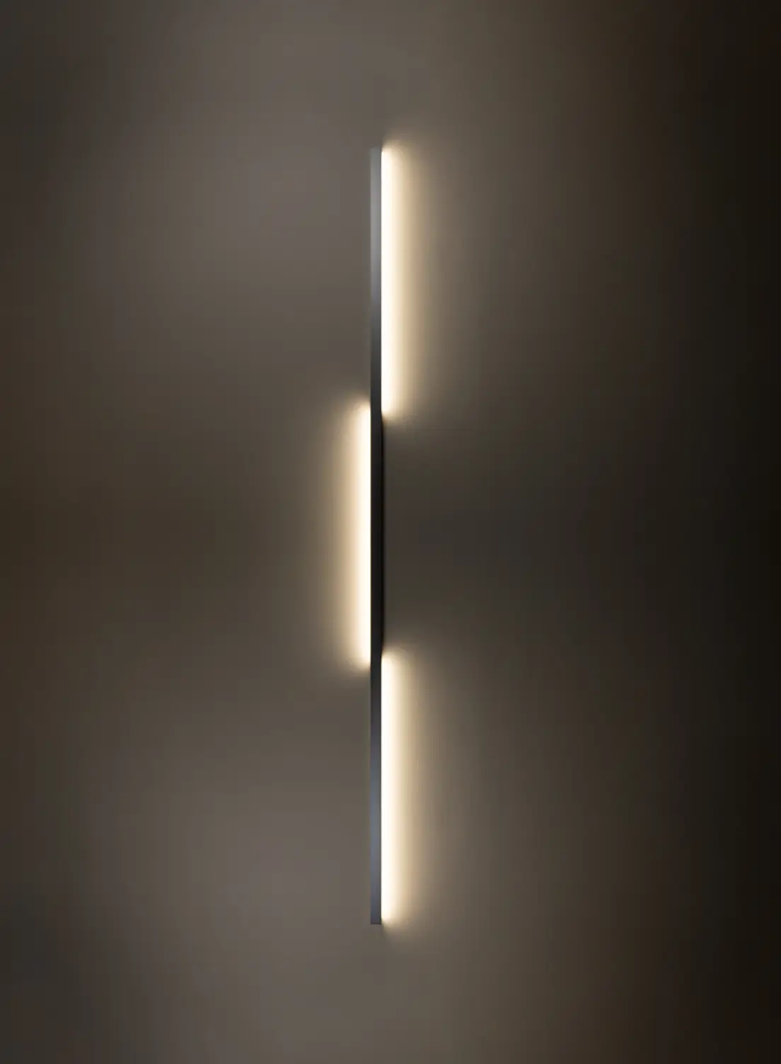Vertikal installierte Wandleuchte GERA Quadra Wall wirft Licht nach links und rechts auf dunkle Wand.