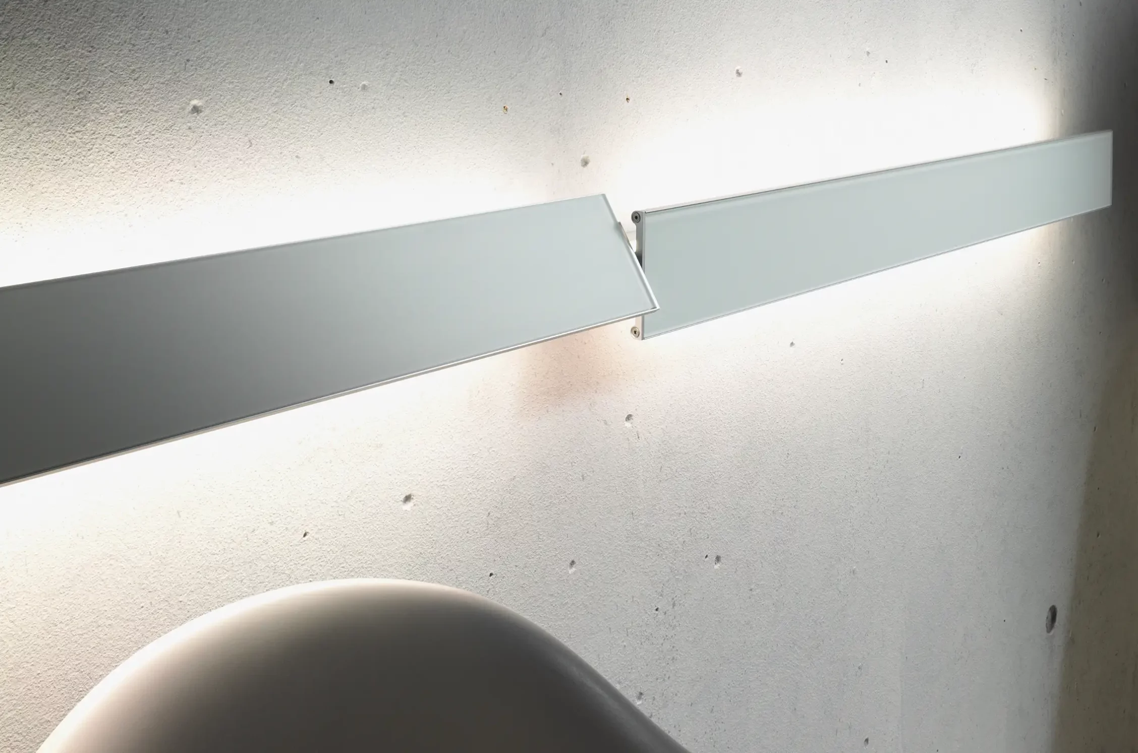 Zwei GERA Slant Leuchten mit unterschiedlicher Winkelung vor Sichtbetonwand.