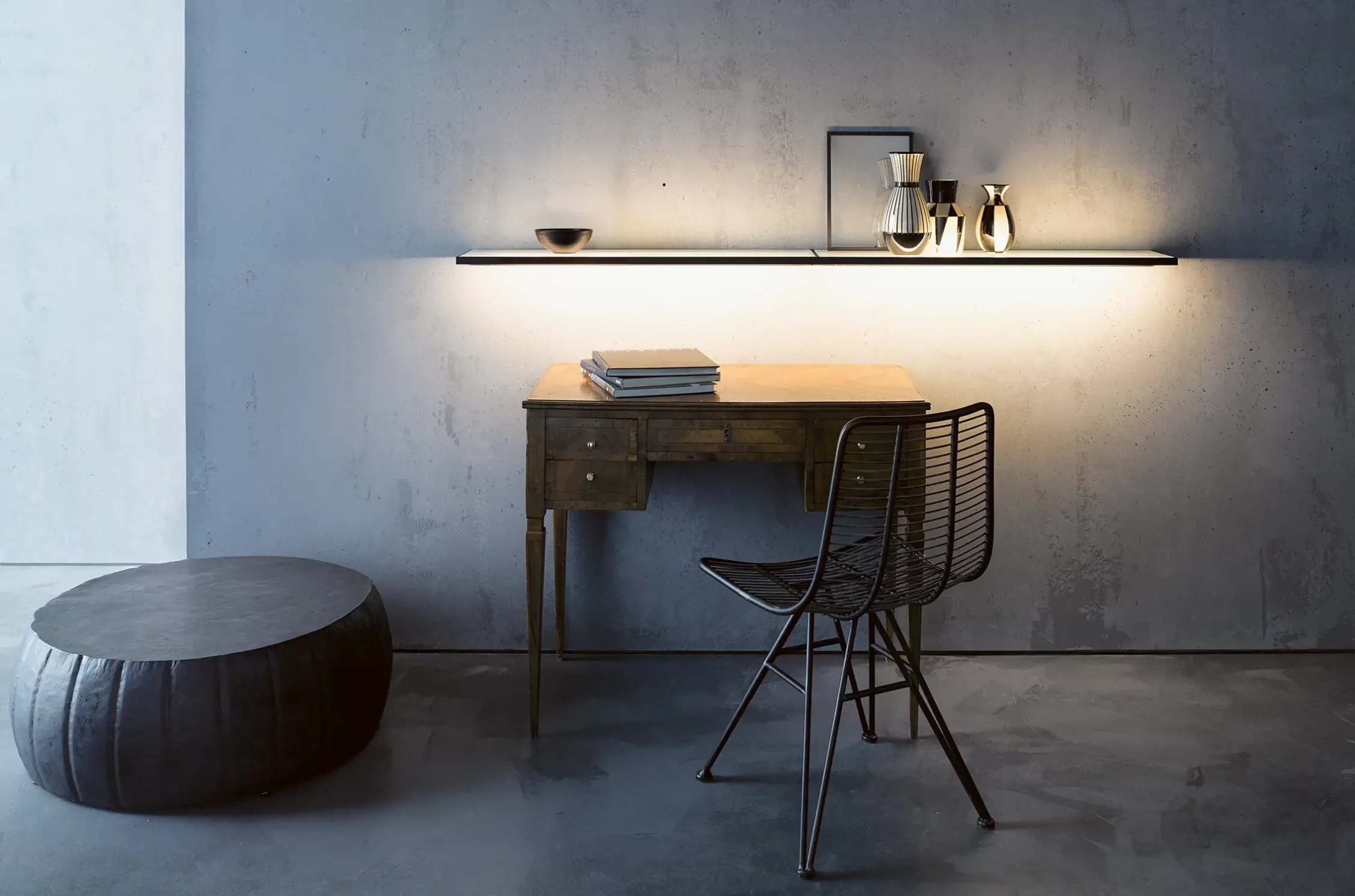 Schreibtisch mit beleuchteter Glasablage GERA Sunrise vor einer grauen Betonwand.