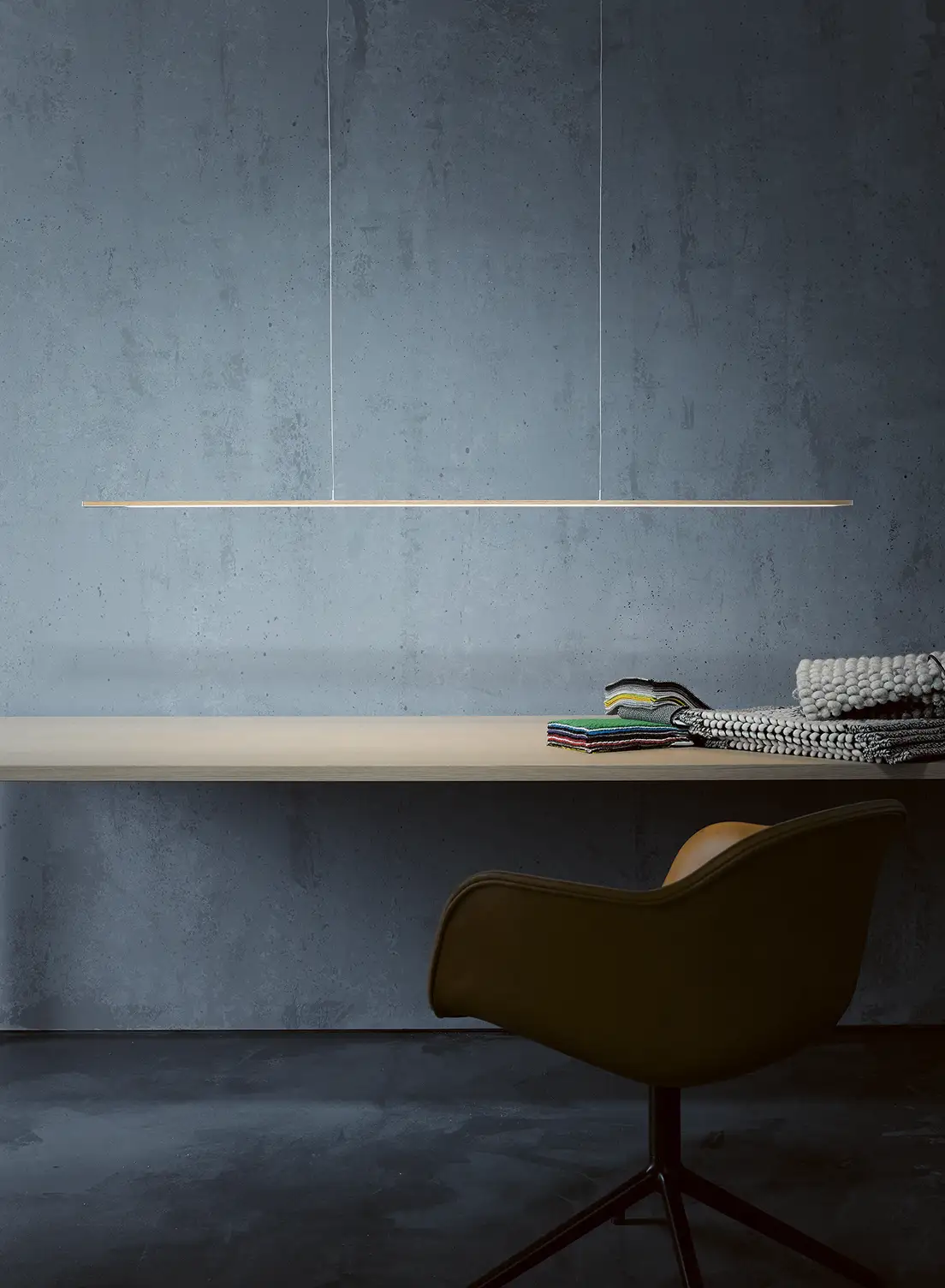 Pendelleuchte GERA Twig über einem hellen Holztisch vor einer grauen Betonwand.